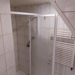 Dusche mit Duschvorhang und Heizkörper an der Wand.