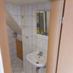 Badezimmer mit Waschbecken, Spiegel und Dusche unter Dachschrägen.