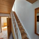 Treppe mit Teppichstufen führt nach oben. Holzdecke und Wandspiegel sichtbar.