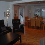 Wohn- und Essbereich mit Ledersofa, Esstisch und Holzboden.