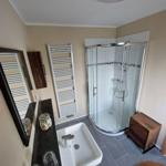 Badezimmer mit Dusche, Waschbecken und Heizkörper.