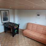 Raum mit Sofa und Tischfußball, Wandbilder und gefliestem Boden.