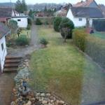 Garten mit Rasenfläche, Steingarten und Pfad zwischen Häusern.