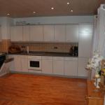 Küche mit weißen Schränken, Holzboden und Edelstahlgeräten.