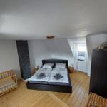 Schlafzimmer mit Doppelbett, Kinderbett und Holzboden.