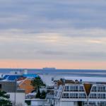 Meeransicht mit Hotel und Schiff im Hintergrund bei Dämmerung.