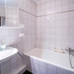 Badezimmer mit Badewanne, Waschbecken und Spiegel.