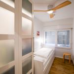 Schlafzimmer mit Bett, Fenster, Stuhl und Deckenventilator.