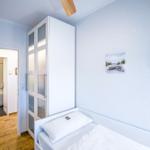 Schlafzimmer mit Bett, Kleiderschrank und Bad im Hintergrund.