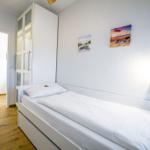 Schlafzimmer mit Bett, Kleiderschrank und Bad im Hintergrund.