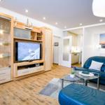 Wohnzimmer mit blauem Sofa, Fernseher und Holzboden.