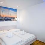 Schlafzimmer mit Doppelbett und Wandbild von Segelyachten.