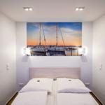 Schlafzimmer mit Bett und Wandbild von Segelbooten.
