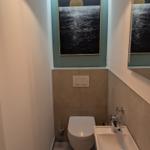 Badezimmer mit Toilette, Waschbecken und Wandbild.