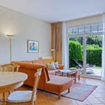 Wohn- und Essbereich mit Sofa, Tisch und Blick auf Garten.