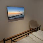 Schlafzimmer mit Bett, Stuhl und Wandbildschirm