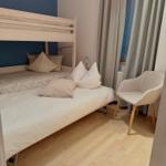 Ein Schlafzimmer mit Doppelbett, Stuhl und Fenster mit Vorhängen.