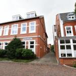 Rotes Backsteinhaus mit weißen Fensterrahmen und Schild Nordseehaus