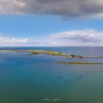 Aerial view of coastal islands with sailboats and a lighthouse.