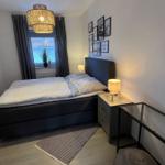 Schlafzimmer mit Bett, Nachttisch, Wandspiegel und Fenster mit Vorhängen.