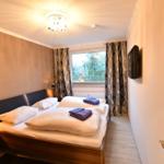 Schlafzimmer mit Doppelbett, Fenster und TV.