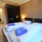 Schlafzimmer mit Doppelbett, blauen Handtüchern und Spiegelschrank.