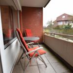 Terrasse mit zwei Stühlen und Tisch, rote Kissen, Blick auf Nachbarhaus.
