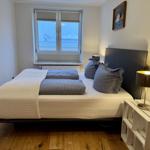 Schlafzimmer mit Bett, Fenster und Nachttisch.