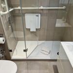 Duschbad mit Rollstuhlgerechter Dusche, Toilette und Waschbecken.