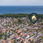 Aerial view of a coastal town with houses and forest near the sea.