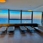 Terrasse mit Liegestühlen und Blick auf das Meer bei Sonnenuntergang.