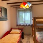 Room with sofa bed, bunk bed, and window with curtains.