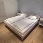 Schlafzimmer mit Doppelbett, zwei Nachttischen und Holzboden.