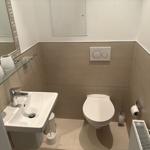 Badezimmer mit Toilette, Waschbecken und Spiegel.