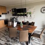 Essbereich mit Holztisch, sechs Stühlen und moderner Hängelampe über dem Tisch.