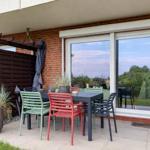 Terrasse mit Tisch und Stühlen, Pergola und Pflanzen vor einer Glasfront.