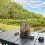 Helle Außenterrasse mit Tisch und Stühlen, Blick auf grünen Garten und Bäume.