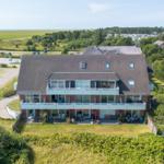 Ein Haus mit Balkon und Terrasse, umgeben von Grünflächen und Wald.