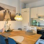 Küche mit Essbereich, weißen Schränken und Holztisch mit Stühlen.