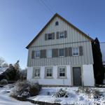 Haus mit Schnee bedecktem Grundstück und Fenstern mit Läden