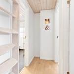 Hallway with wooden ceiling, white walls, and hardwood floor. An ampersand sign hangs on the wall.