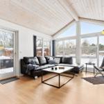 Living room with black leather sofa, large windows and wooden floor. Snow outside.