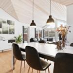 Dining area with white table, black chairs, and large window view. Light wood ceiling and wall art.