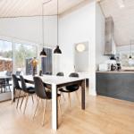 Dining area with table and chairs, kitchen with countertop and windows.