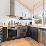 Kitchen with black cabinets, stainless steel appliances, and wooden floor. Windows with view of forest.