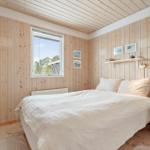 A bedroom with wooden walls, a bed, and a window.