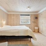 Bedroom with wooden walls, bed, and window. A desk is next to the bed.