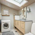 Bathroom with washing machine, sink, and toilet under skylight.