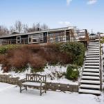 Snow-covered stairs lead to a house with a balcony and garden.
