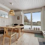 Dining room with wooden table, chairs, and large window. Outside is snow-covered.